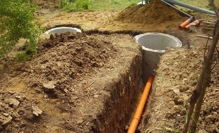 Csatlakozás egy csővezetékhez egy kétkamrás, betongyűrűkből készült szeptikus tartályhoz Árokásás árokás közben