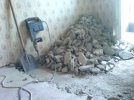 Smantellamento del vecchio massetto di fronte al dispositivo di riscaldamento a pavimento Pulizia del rivestimento prima dell'installazione