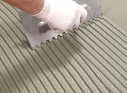 Posa di piastrelle per pavimenti su un pavimento caldo Applicazione della colla