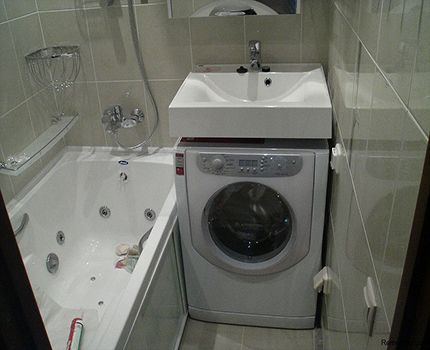 El lavabo del bany està muntat per sobre de la rentadora. El nenúfar s’enfonsa a la petita banyera