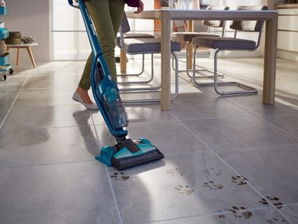 Vacuuming isang sahig sa kusina na may washing function Nililinis ang kusina gamit ang isang vacuum cleaner