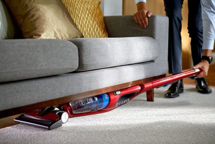 Pembersihan habuk dari bawah sofa dengan pembersih vakum menegak Pembersihan perabot