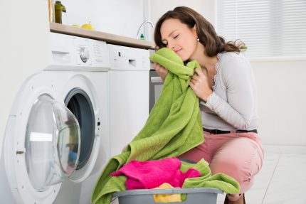 Retirer le linge après le lavage Femme prend le linge de la laveuse