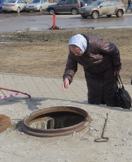 Sewer well service Elderly woman looks in the sewer